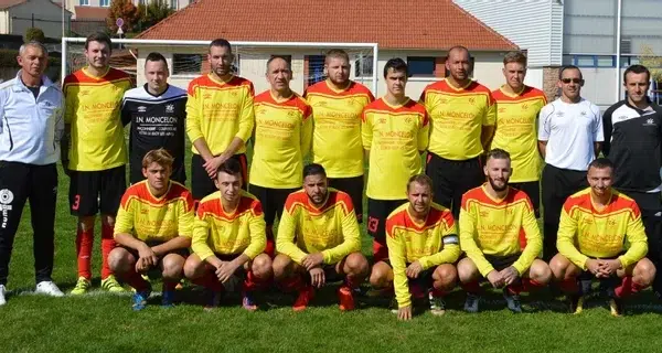 Equipe de foot posant fièrement devant les cages en maillot rouge et jaune