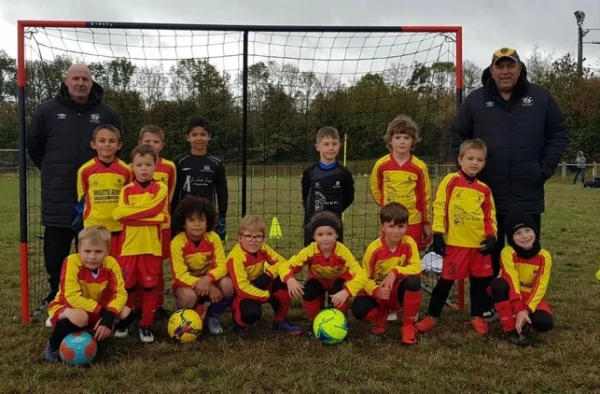 Jeunes joueurs de foot en maillot jaune et rouge devant les cages