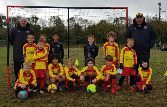 Jeunes joueurs de foot en maillot jaune et rouge devant les cages